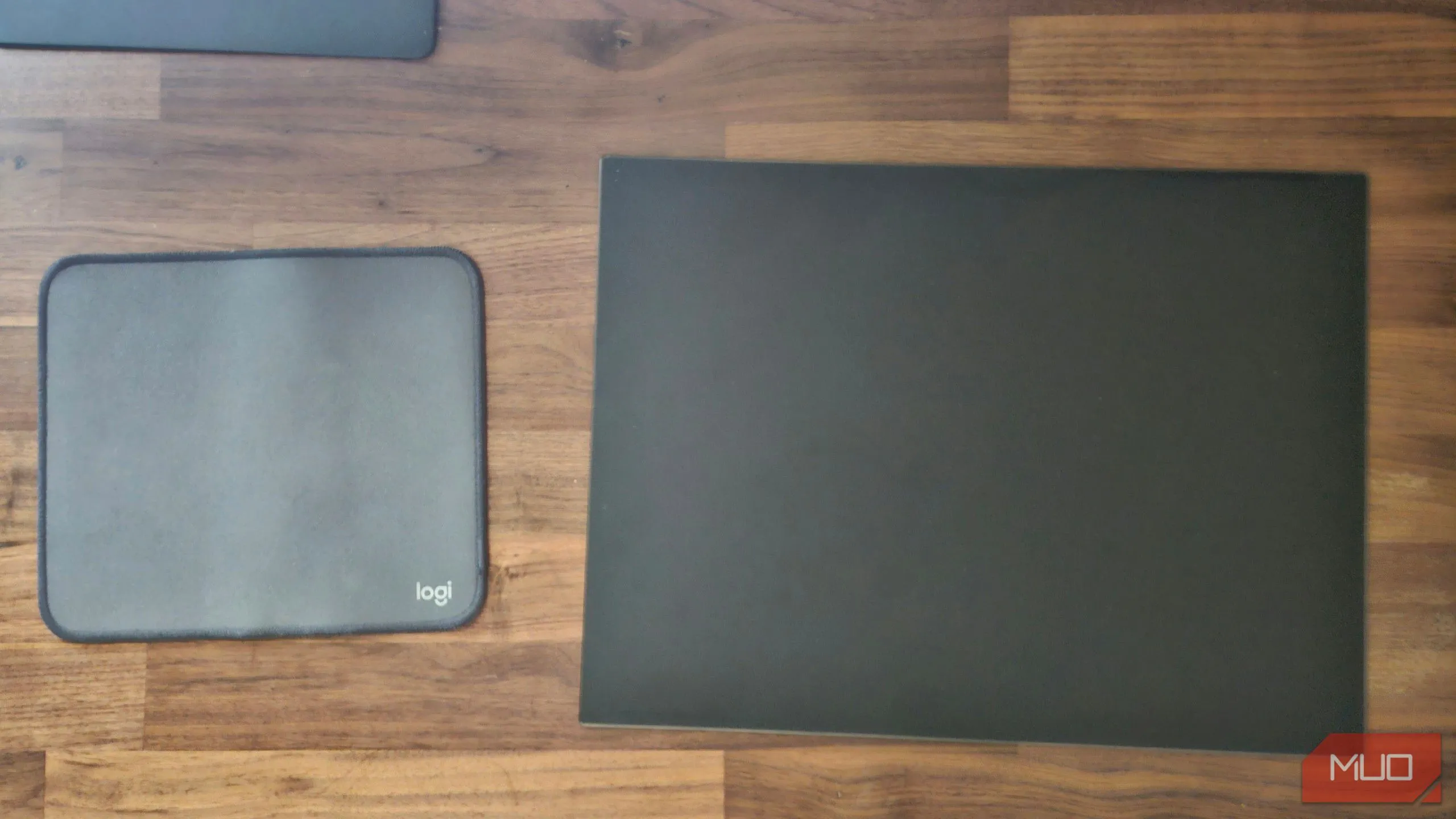 Bàn di chuột Logitech chất liệu vải cạnh bàn di chuột kính cường lực màu đen, minh họa sự khác biệt về thẩm mỹ và chất liệu giữa hai loại pad chuột