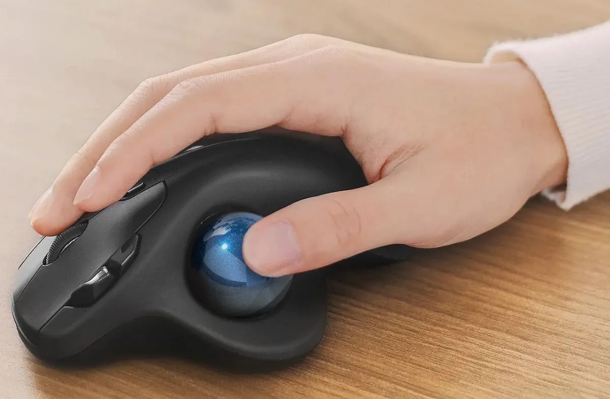 Bàn tay người dùng đang điều khiển chuột trackball loại dùng ngón cái, minh họa cách sử dụng chuột bi lăn công thái học.