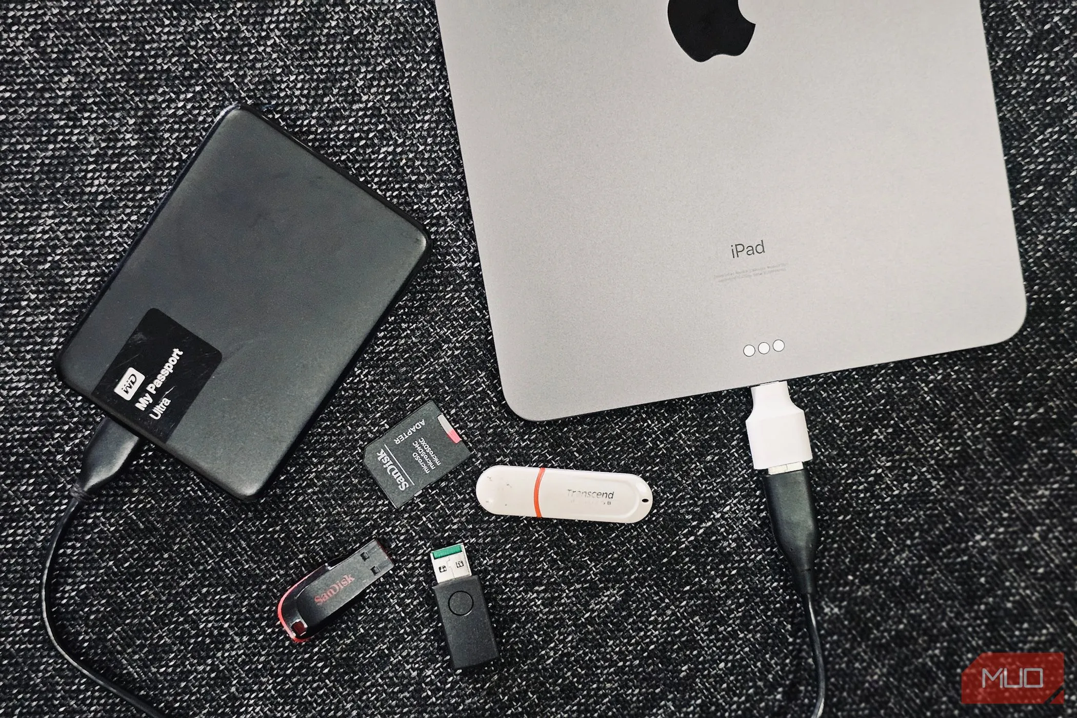 Các ổ đĩa cứng ngoài (HDD/SSD) được kết nối cạnh iPad, minh họa việc sao lưu dữ liệu kép.