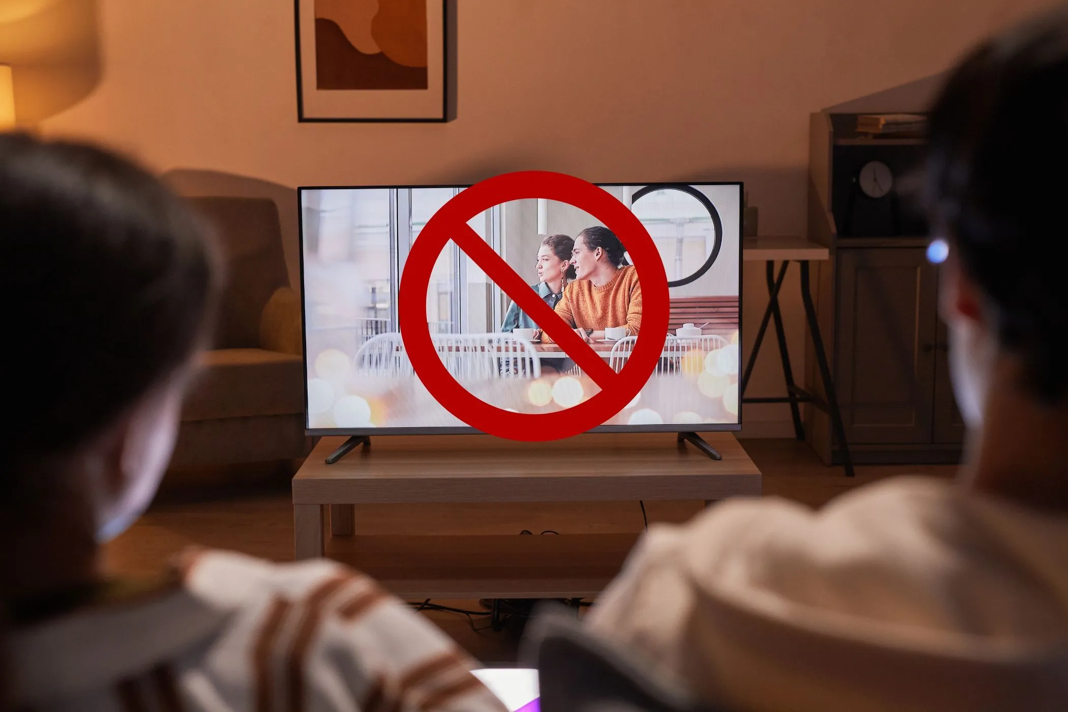 Cặp đôi xem TV với biểu tượng gạch chéo trên màn hình, tượng trưng cho việc vô hiệu hóa tính năng theo dõi trên Smart TV