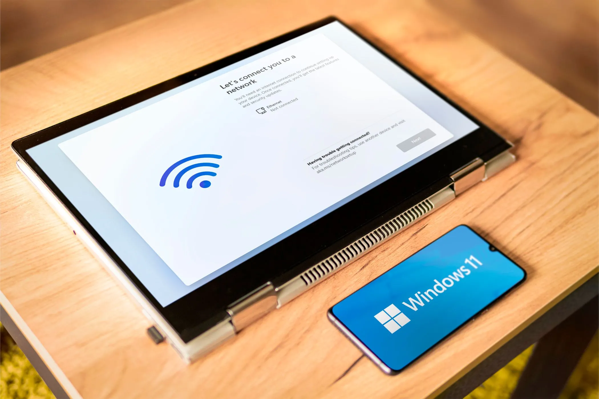 Điện thoại Android đặt cạnh laptop đang cài đặt Windows 11, minh họa khả năng trở thành màn hình phụ cho PC