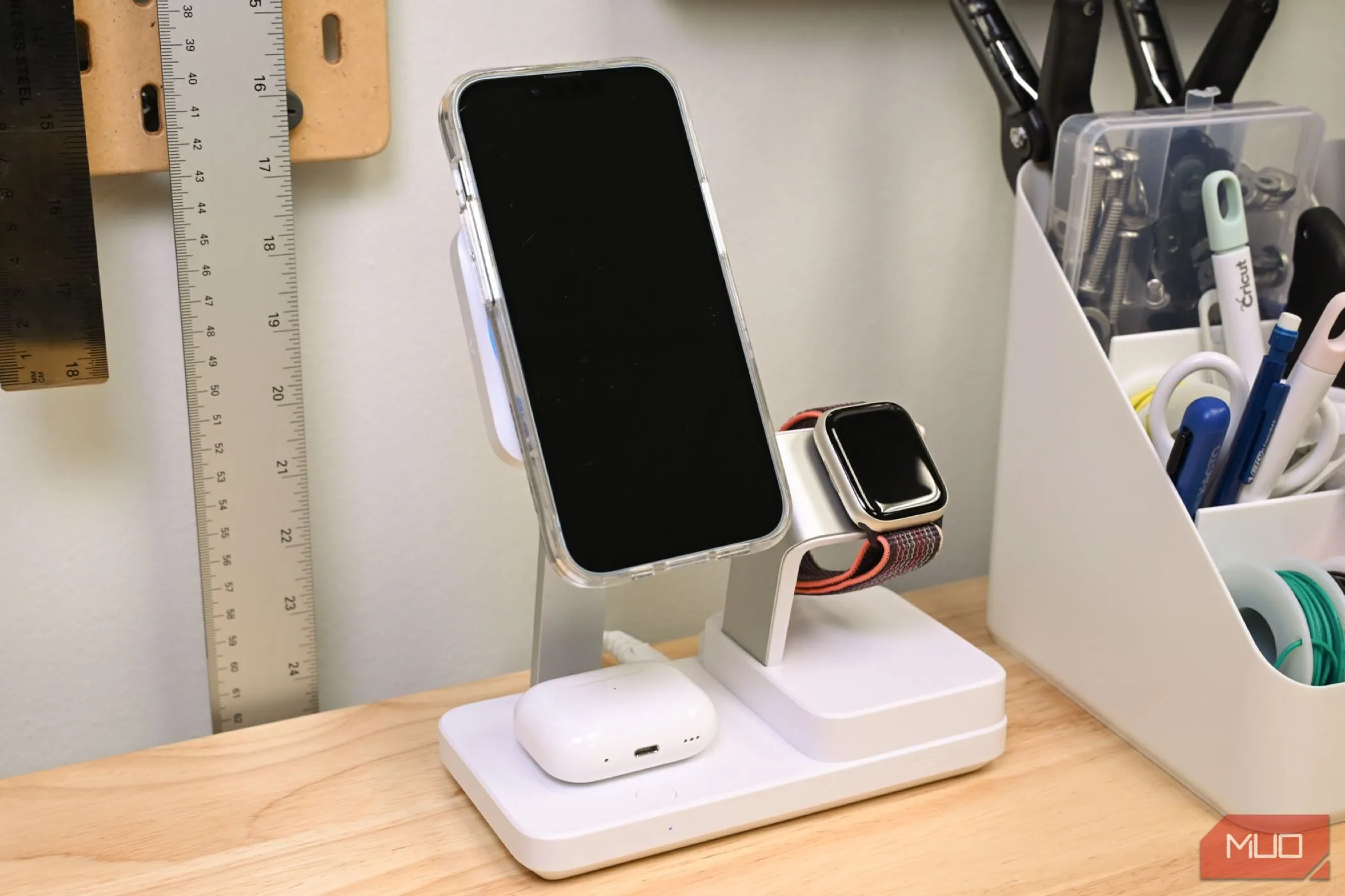 Điện thoại iPhone, tai nghe AirPods và đồng hồ Apple Watch đang sạc cùng lúc trên đế sạc không dây đa năng Qi2, minh họa tính tiện lợi của phụ kiện sạc từ tính.