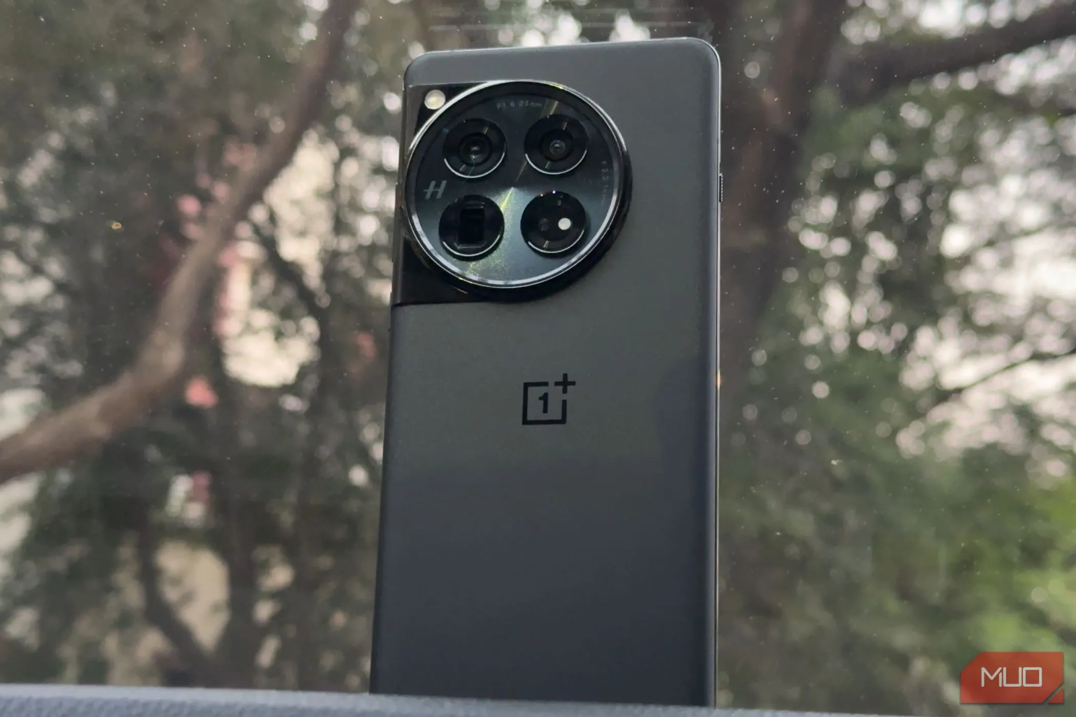 Điện thoại OnePlus 12 màu đen đặt trên bảng điều khiển xe hơi, thể hiện thiết kế sang trọng