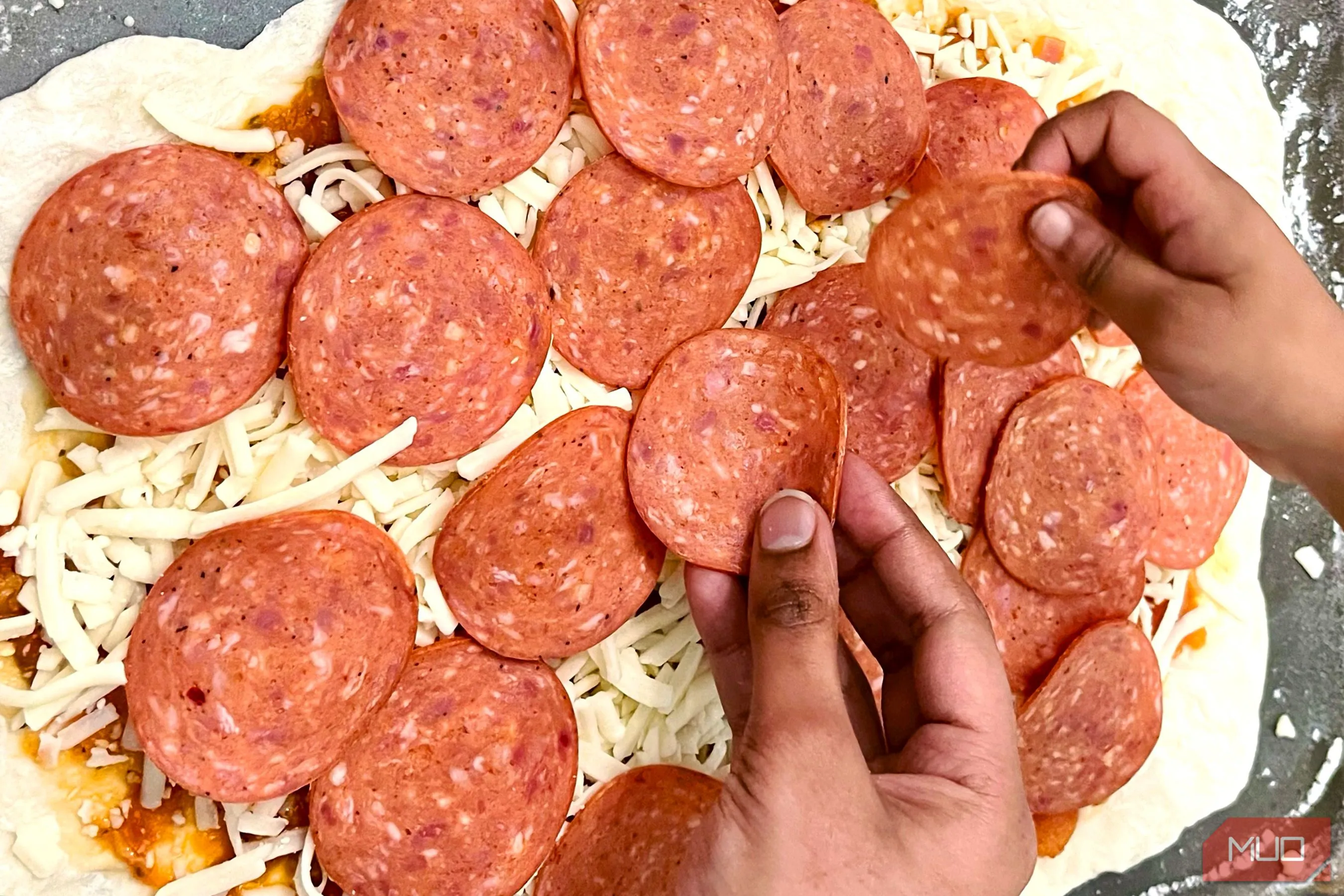 Đôi bàn tay đang làm pizza, tạo nên câu chuyện và cảm xúc cho bức ảnh ẩm thực, thể hiện yếu tố con người trong nhiếp ảnh món ăn.