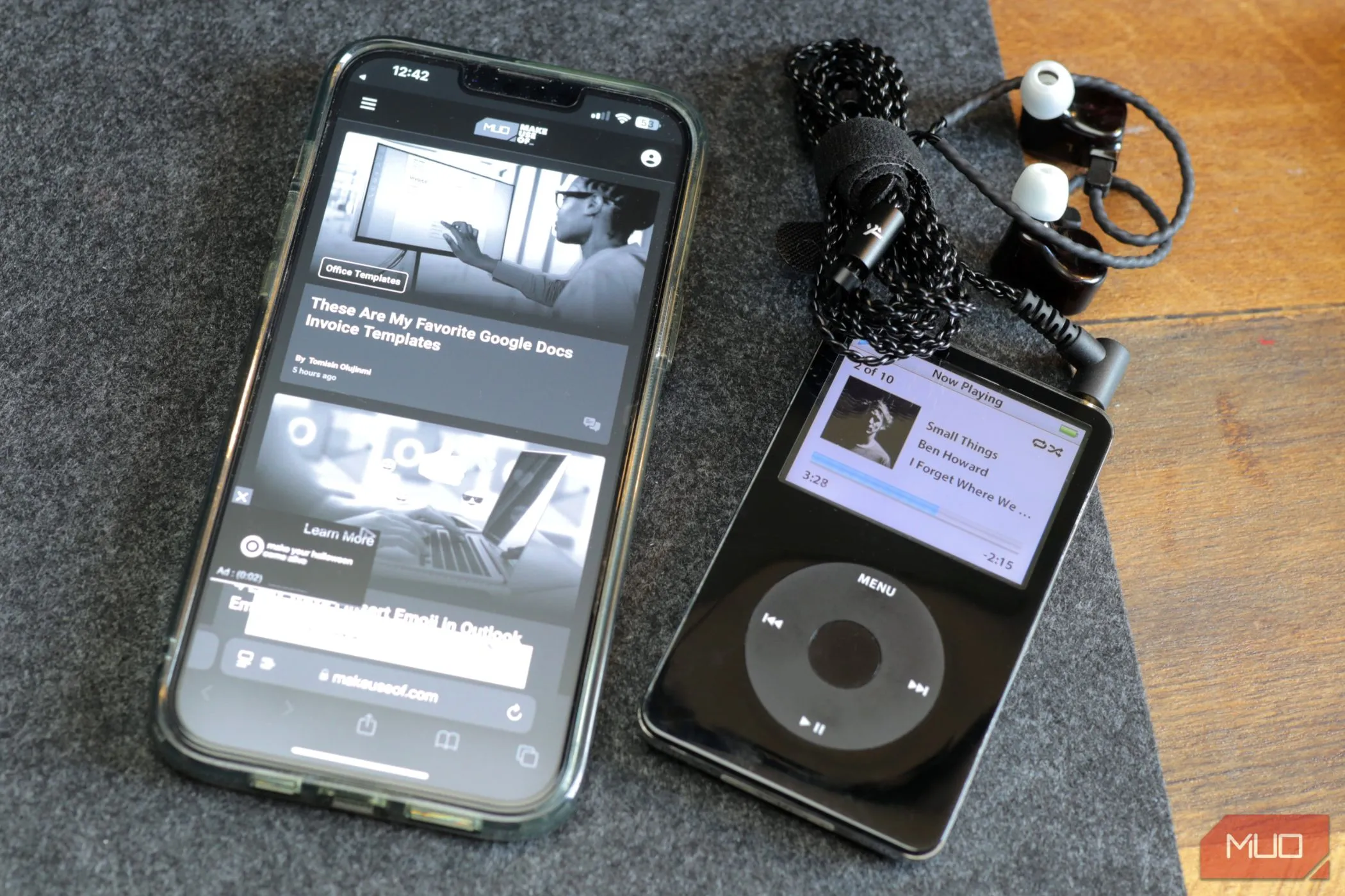 Giao diện đen trắng của iPhone 13 cạnh một chiếc iPod màu đen trên bàn làm việc, gợi ý việc chuyển đổi iPhone cũ thành máy nghe nhạc chuyên dụng