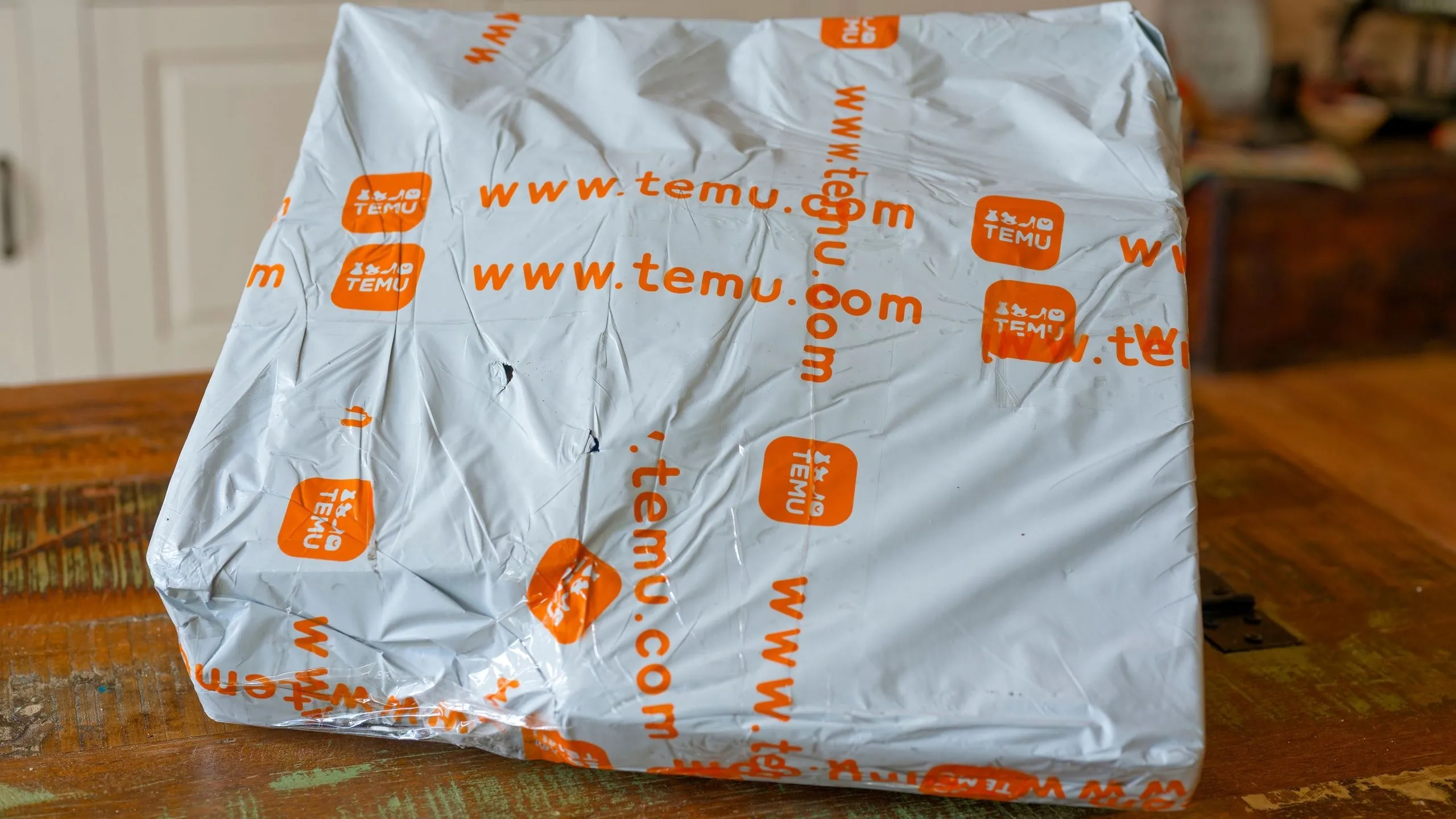 Gói hàng Temu đặt trên bàn, tượng trưng cho việc điều chỉnh giá bán và ảnh hưởng từ chính sách thuế quan mới.