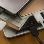 Hình ảnh nhiều ổ cứng rời bên cạnh laptop minh họa sự phức tạp khi quản lý lưu trữ không hiệu quả
