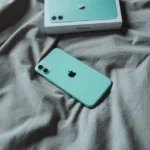 iPhone 11 màu xanh mint nằm trên chăn, thể hiện chất lượng hoàn thiện bền bỉ