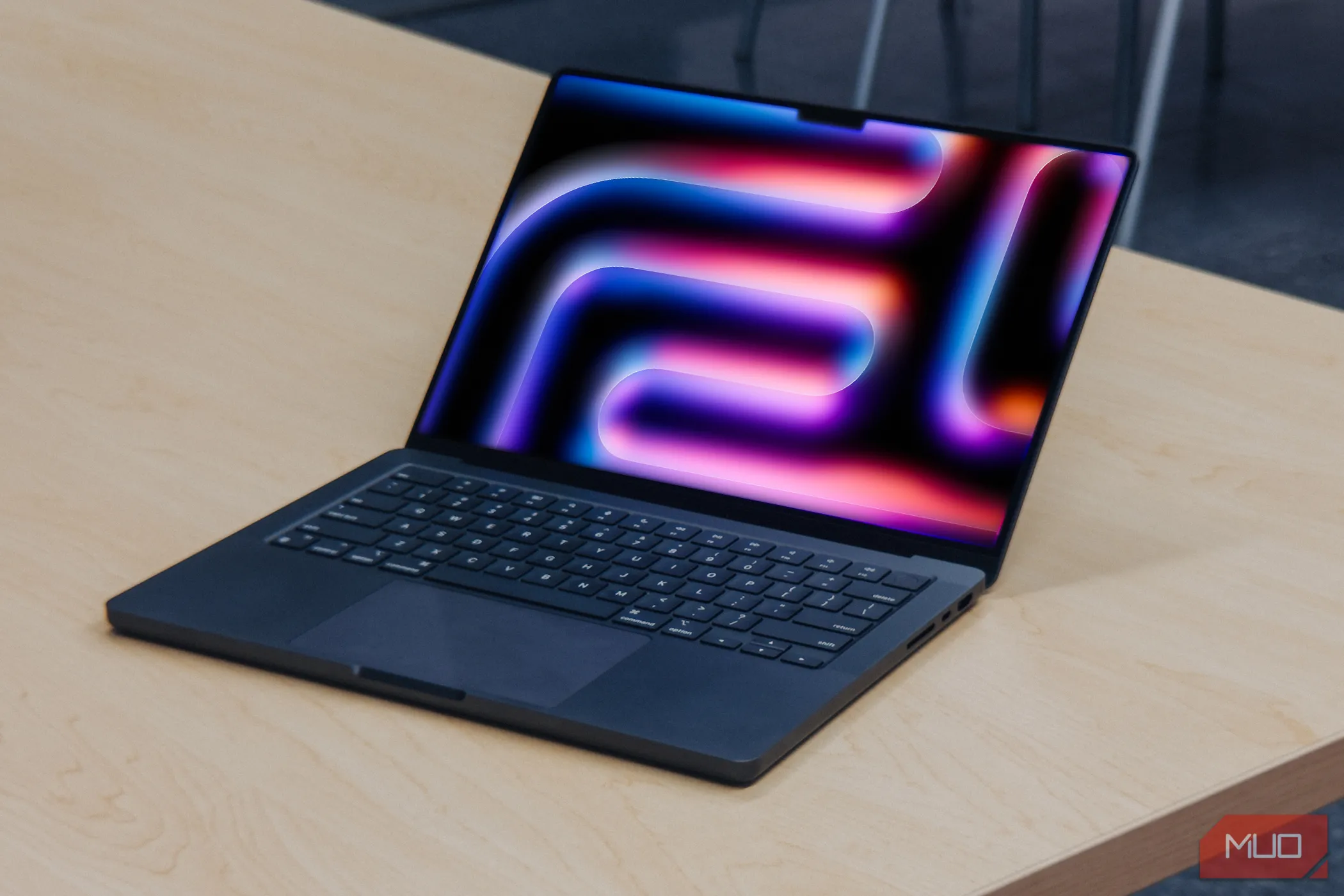 MacBook Pro M4 với màn hình nghiêng trên bàn gỗ, tượng trưng cho thế hệ Mac mới chạy Apple Silicon