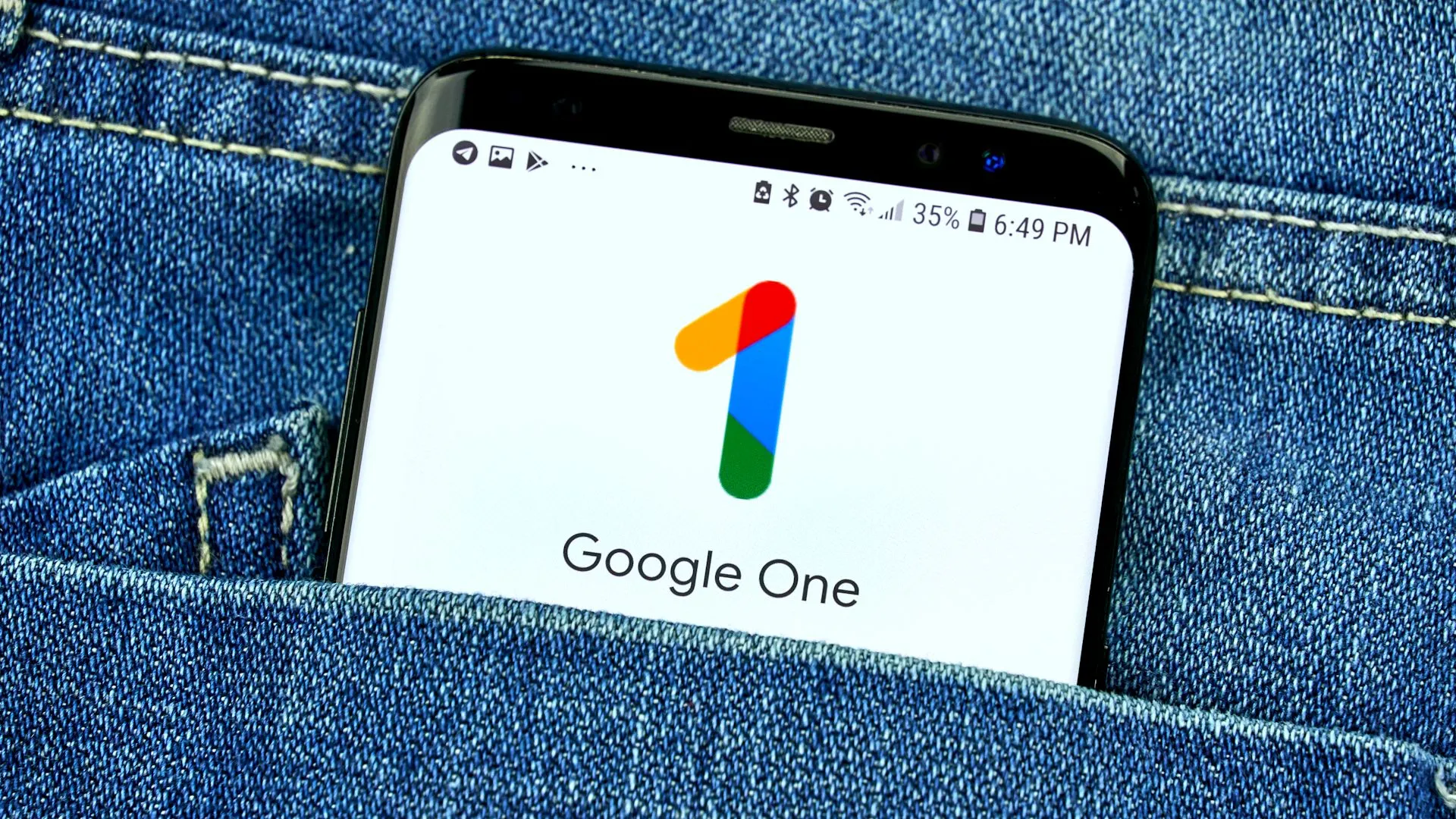 Màn hình điện thoại hiển thị ứng dụng Google One trong túi quần jean, minh họa việc sử dụng dịch vụ đám mây trả phí như một lớp sao lưu dữ liệu cuối cùng.