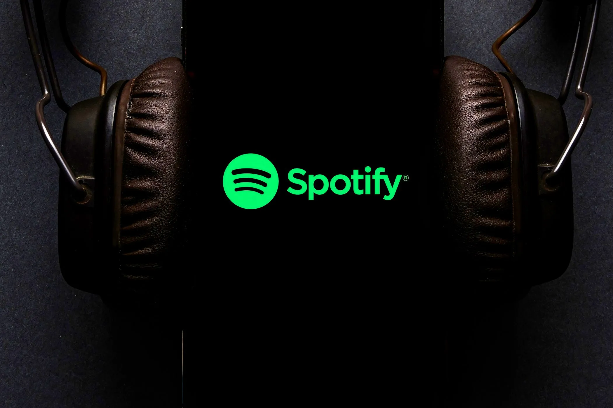Màn hình điện thoại hiển thị ứng dụng Spotify đang phát nhạc, tai nghe được cắm vào điện thoại, minh họa khả năng điều khiển Spotify trên Google Maps khi lái xe an toàn.