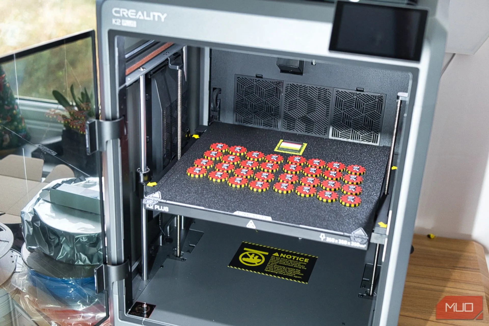 Máy in 3D Creality K2 Plus và hệ thống CFS đặt trên bàn với các vật phẩm đa màu sắc đã hoàn thành