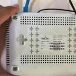 Một bàn tay cầm router và chỉ mặt sau của nó