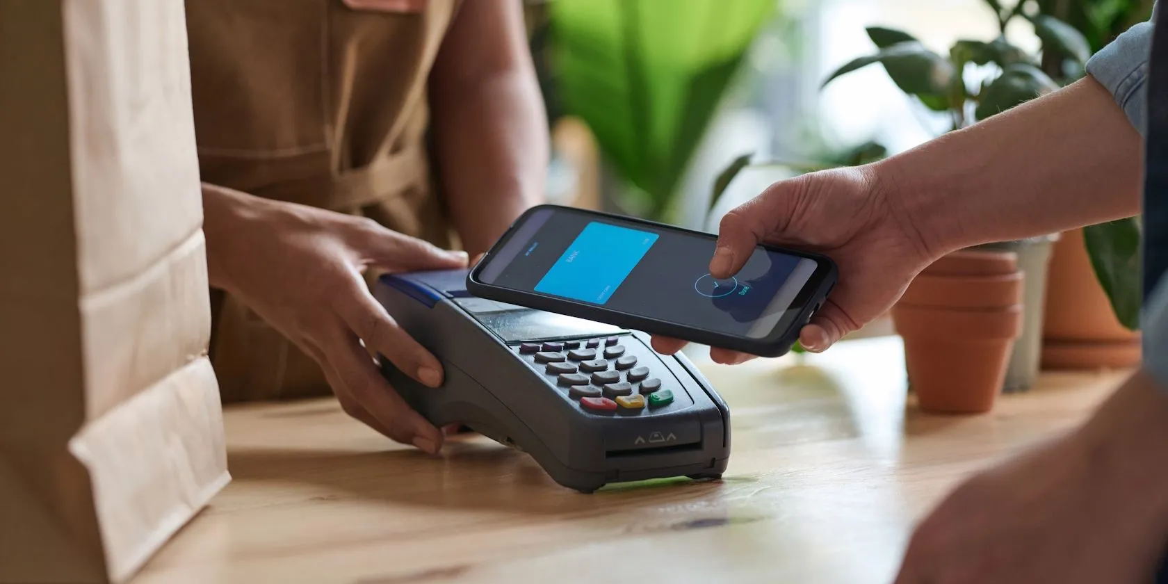 Một người đàn ông đang thực hiện thanh toán không tiếp xúc bằng điện thoại thông minh qua chip NFC tại quầy thu ngân siêu thị.
