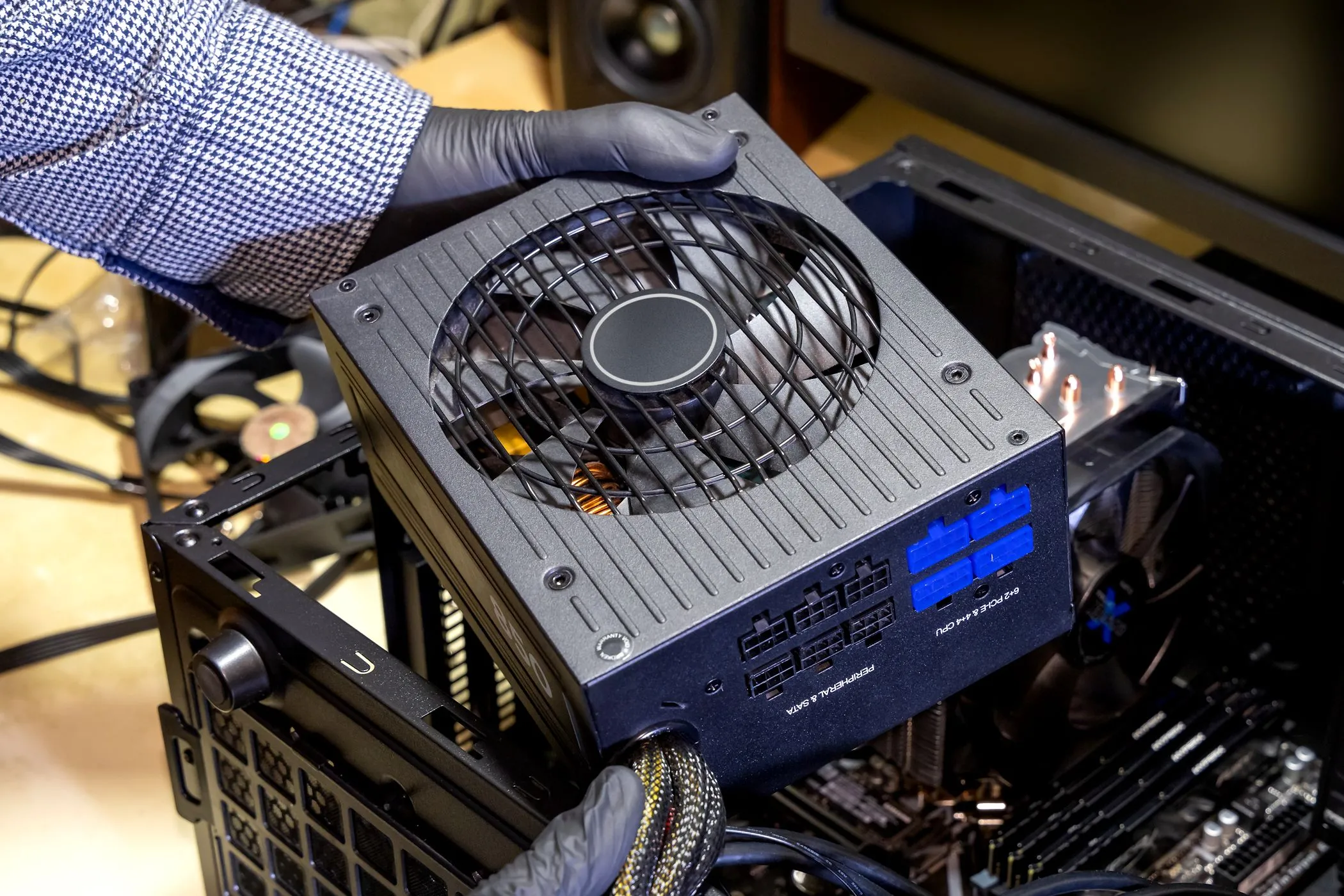 Một người đang lắp bộ nguồn (PSU) vào vỏ máy tính để bàn, minh họa việc lựa chọn nguồn điện chất lượng