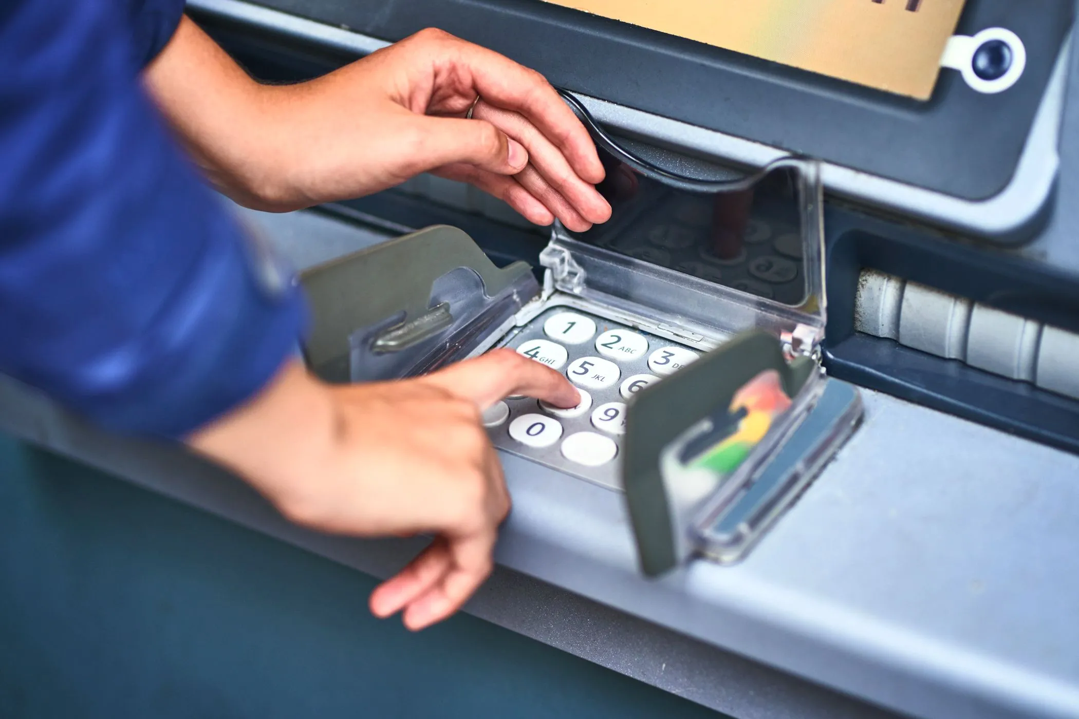 Một người đang nhập mã PIN trên bàn phím máy ATM, minh họa hành vi sử dụng ATM có nguy cơ bị skimming.