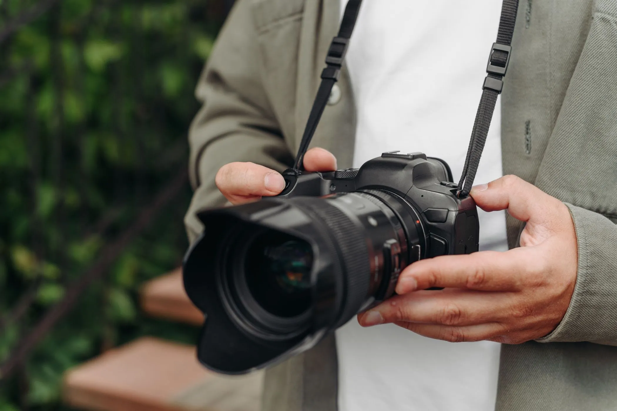 Một nhiếp ảnh gia trẻ tuổi đang cầm chắc chiếc máy ảnh DSLR trên tay, thể hiện sự chắc chắn và độ bền của thiết bị trong quá trình sử dụng.
