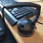 Mouse bungee màu đen đặt trên bàn gỗ, giúp giữ dây chuột gọn gàng cho game thủ