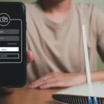 Người đàn ông cầm điện thoại bên cạnh router, minh họa việc thiết lập mạng Wi-Fi ẩn để bảo mật