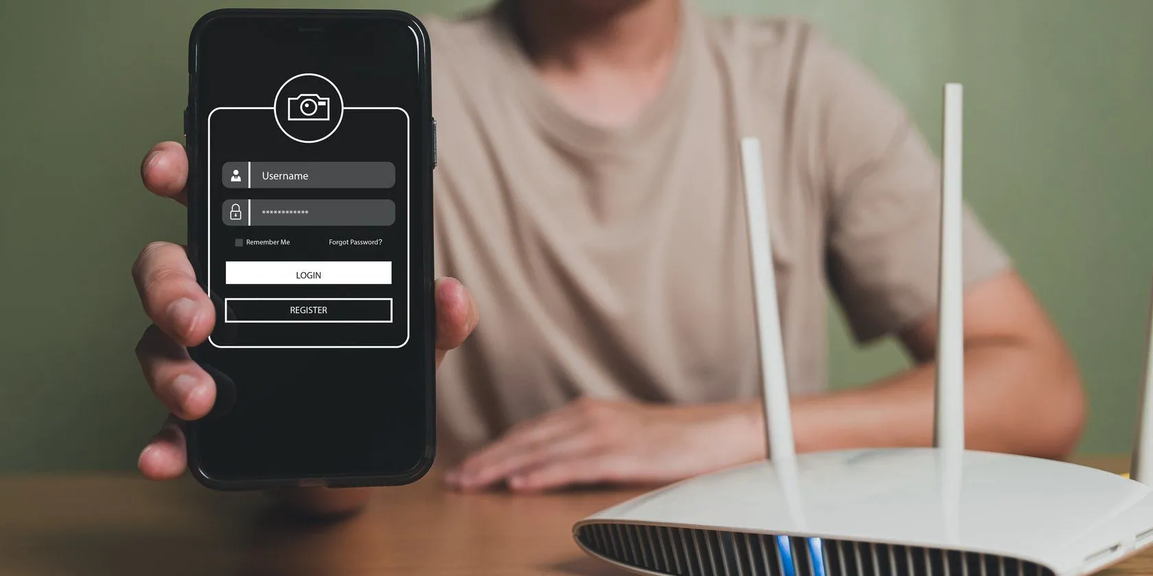 Người đàn ông cầm điện thoại bên cạnh router, minh họa việc thiết lập mạng Wi-Fi ẩn để bảo mật