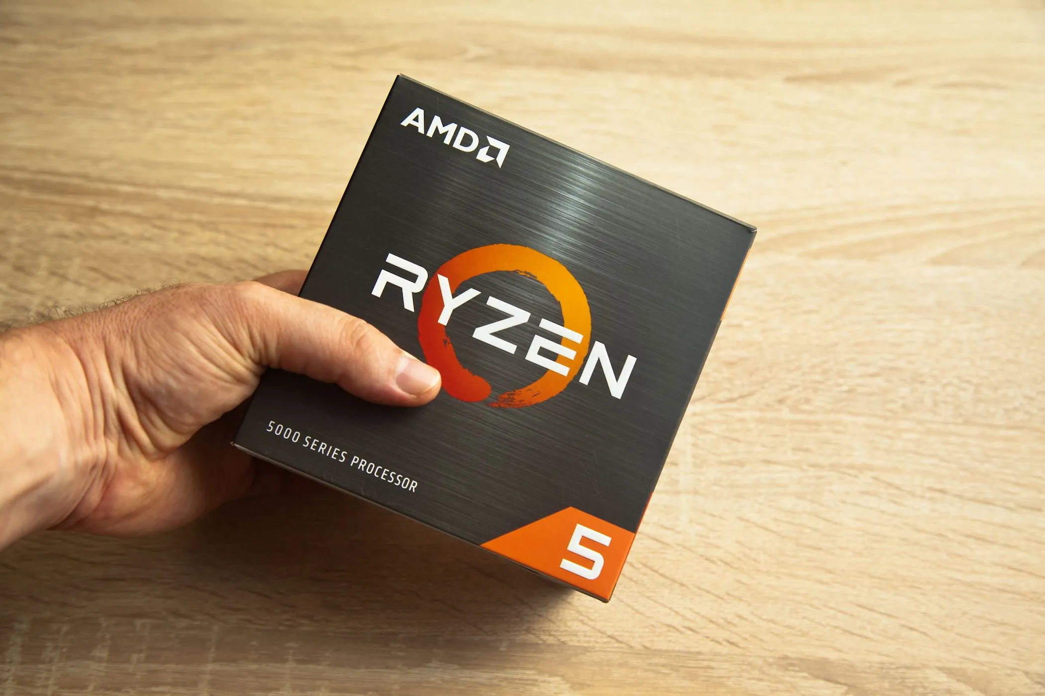 Người đàn ông cầm hộp chip AMD Ryzen 5, minh họa bộ vi xử lý hiệu năng cho laptop giá rẻ.