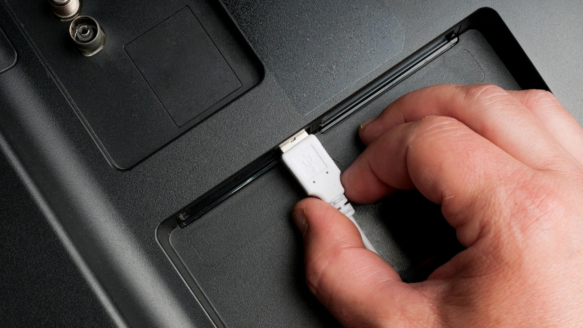 Người đàn ông đang cắm cáp USB Type-A vào cổng TV phía sau