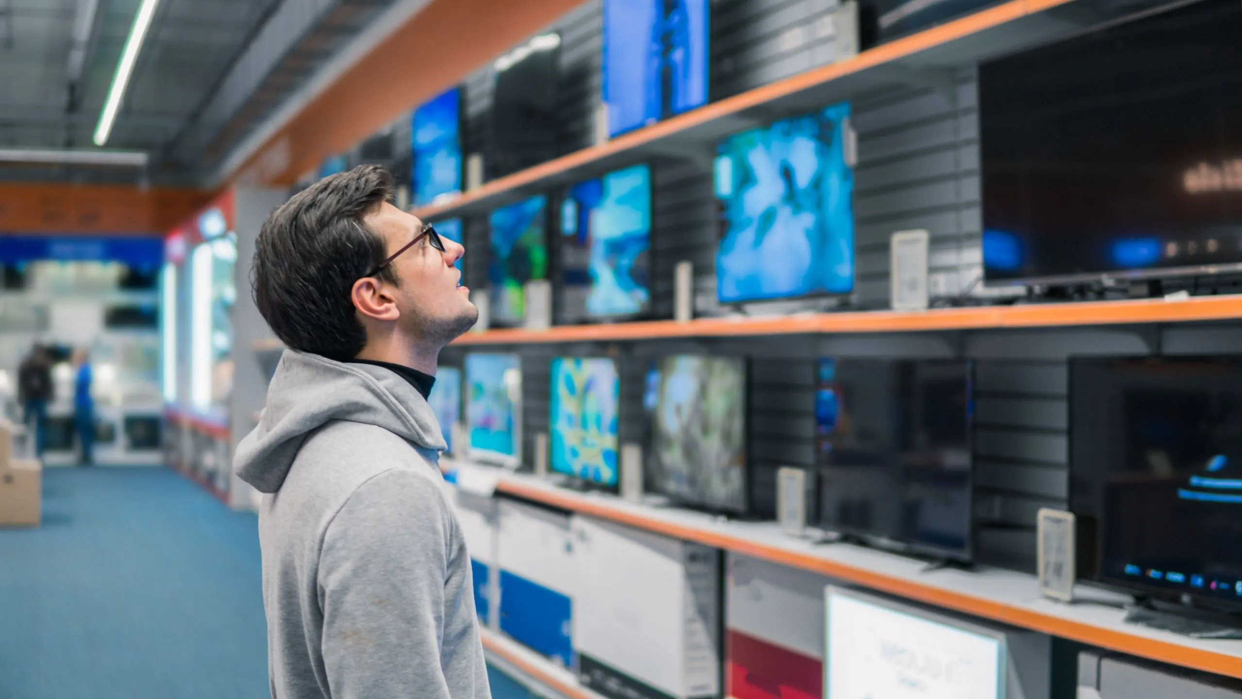 Người đàn ông đang xem các kệ TV thông minh trong cửa hàng