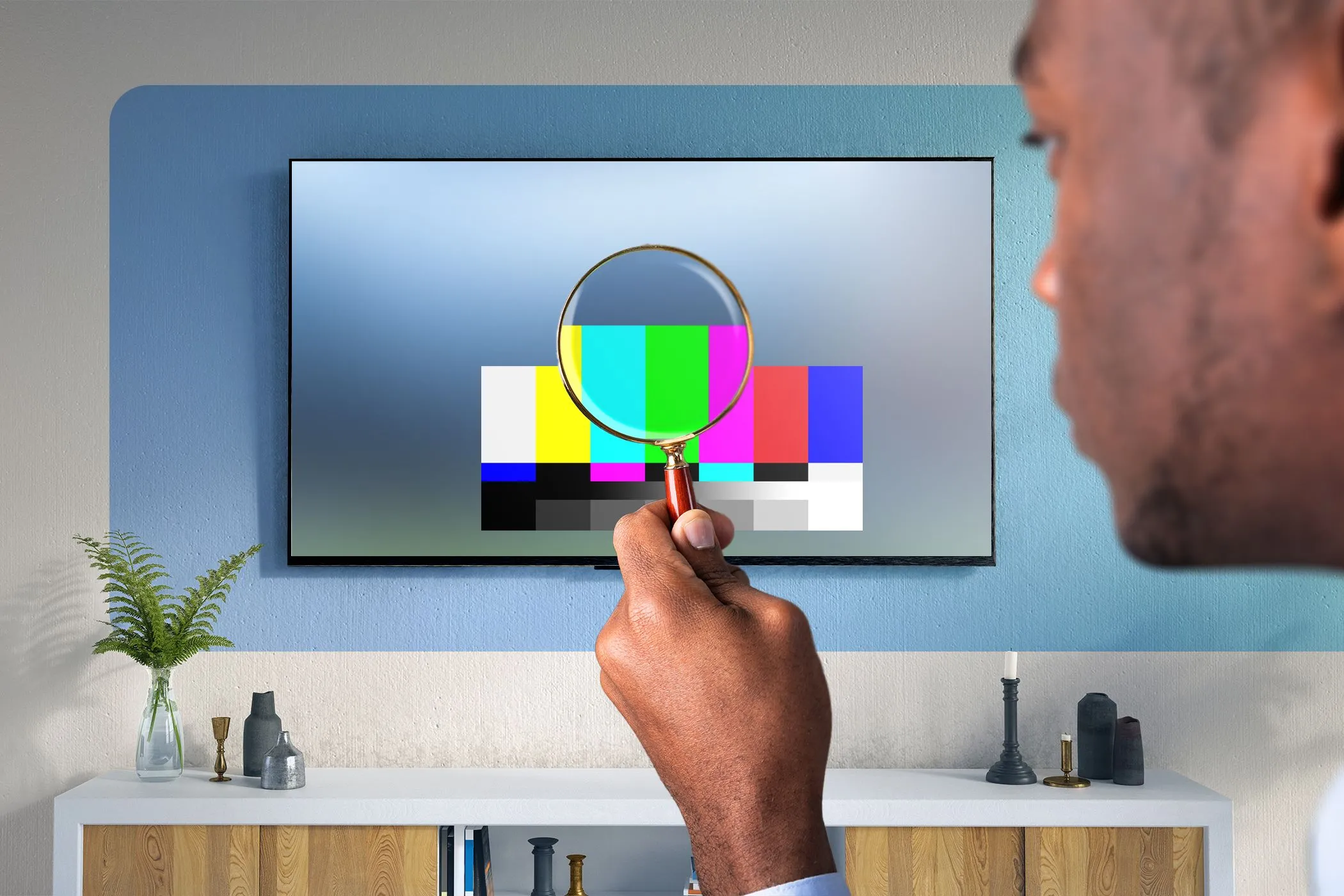 Người đàn ông dùng kính lúp kiểm tra chi tiết hình ảnh trên TV, minh họa sự cần thiết của gam màu rộng