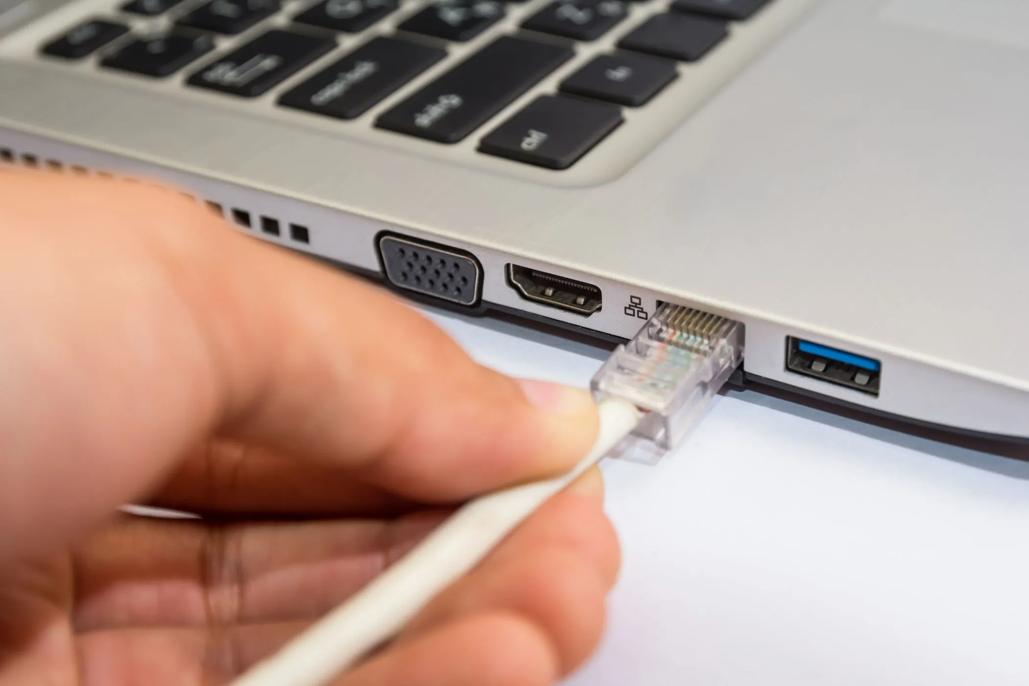 Người đàn ông kết nối cáp mạng Ethernet vào máy tính xách tay Windows để truy cập internet an toàn hơn.