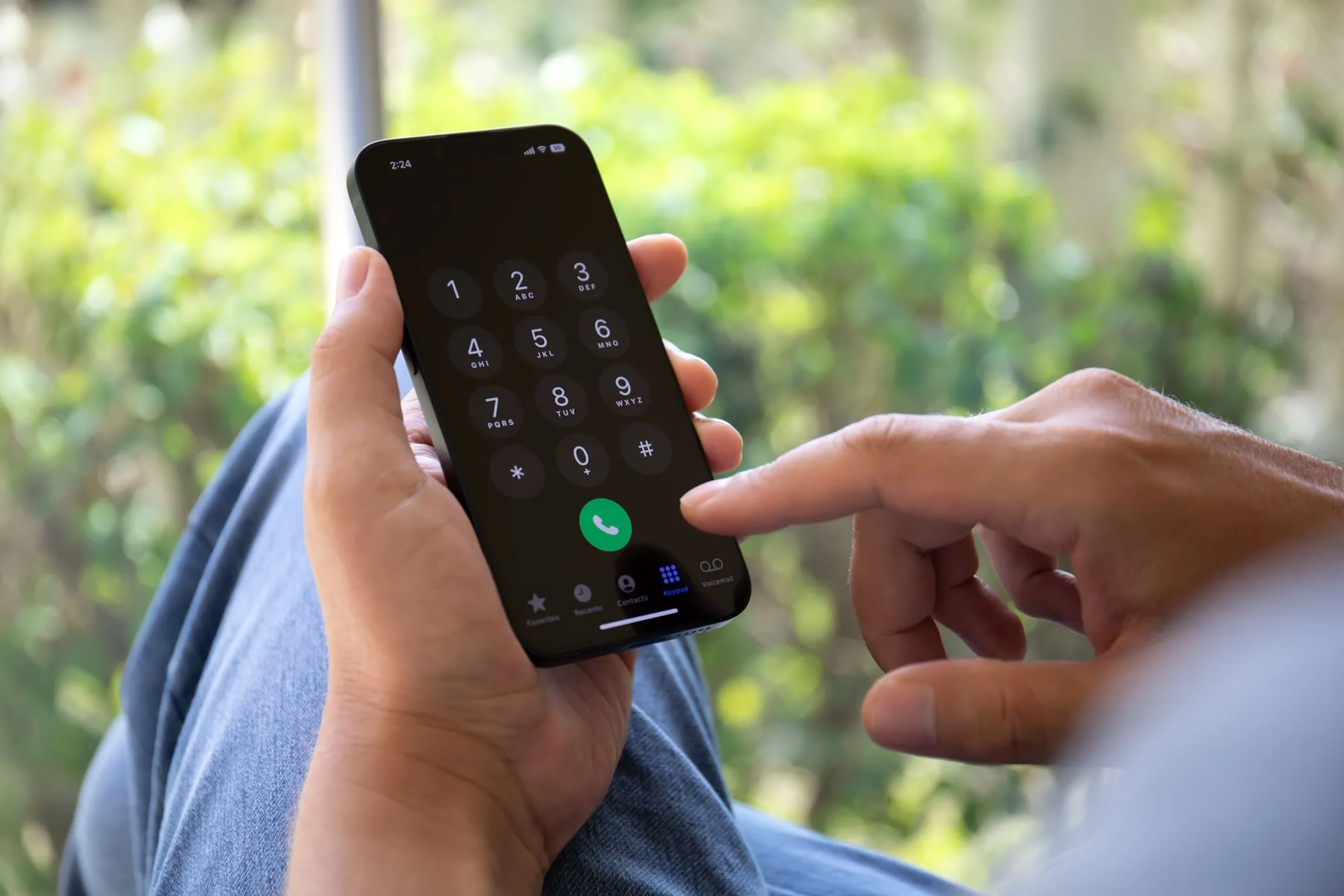 Người đàn ông nhập số điện thoại trên iPhone, thể hiện sự phụ thuộc của xác thực SMS vào sóng di động