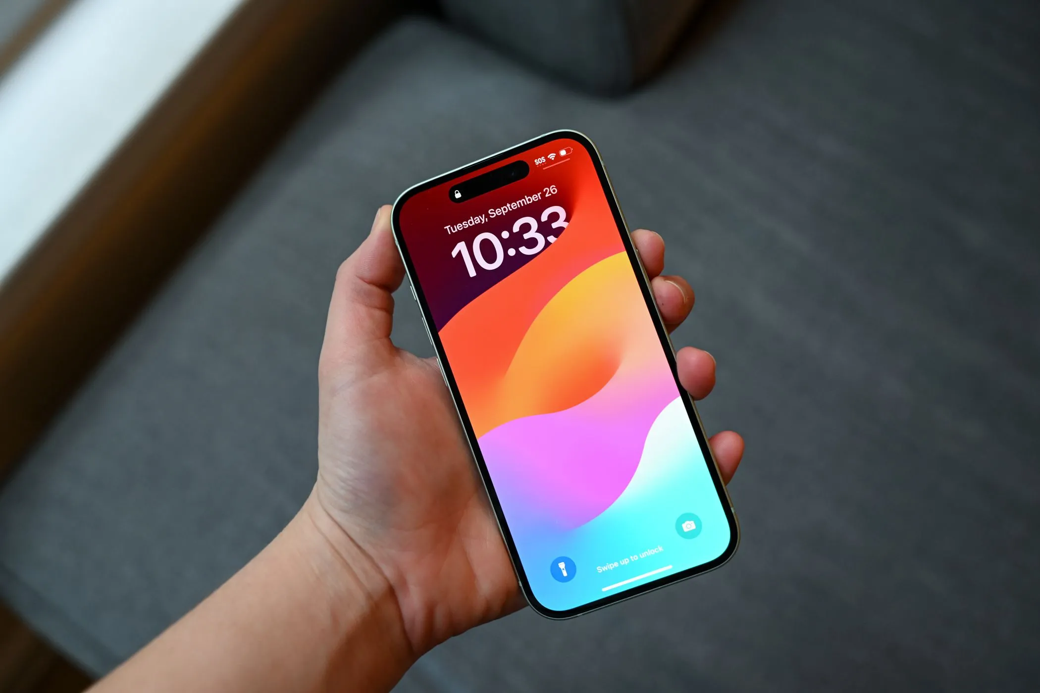 Người dùng cầm iPhone 15 có màn hình khóa với miếng dán riêng tư