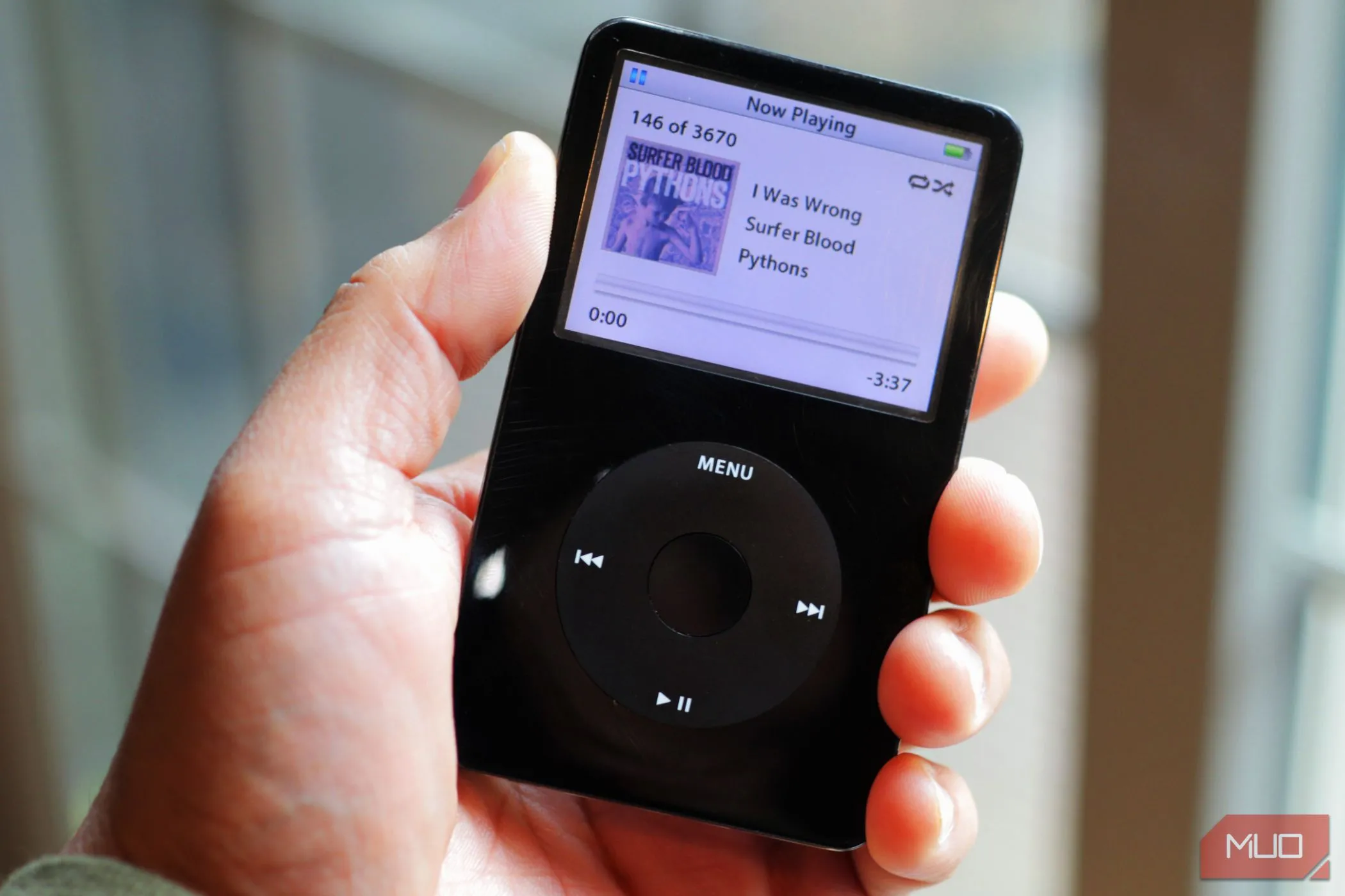 Người dùng đang cầm máy nghe nhạc iPod Classic màu đen gần cửa sổ