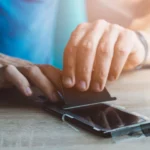 Người dùng đang dán miếng bảo vệ màn hình lên iPhone