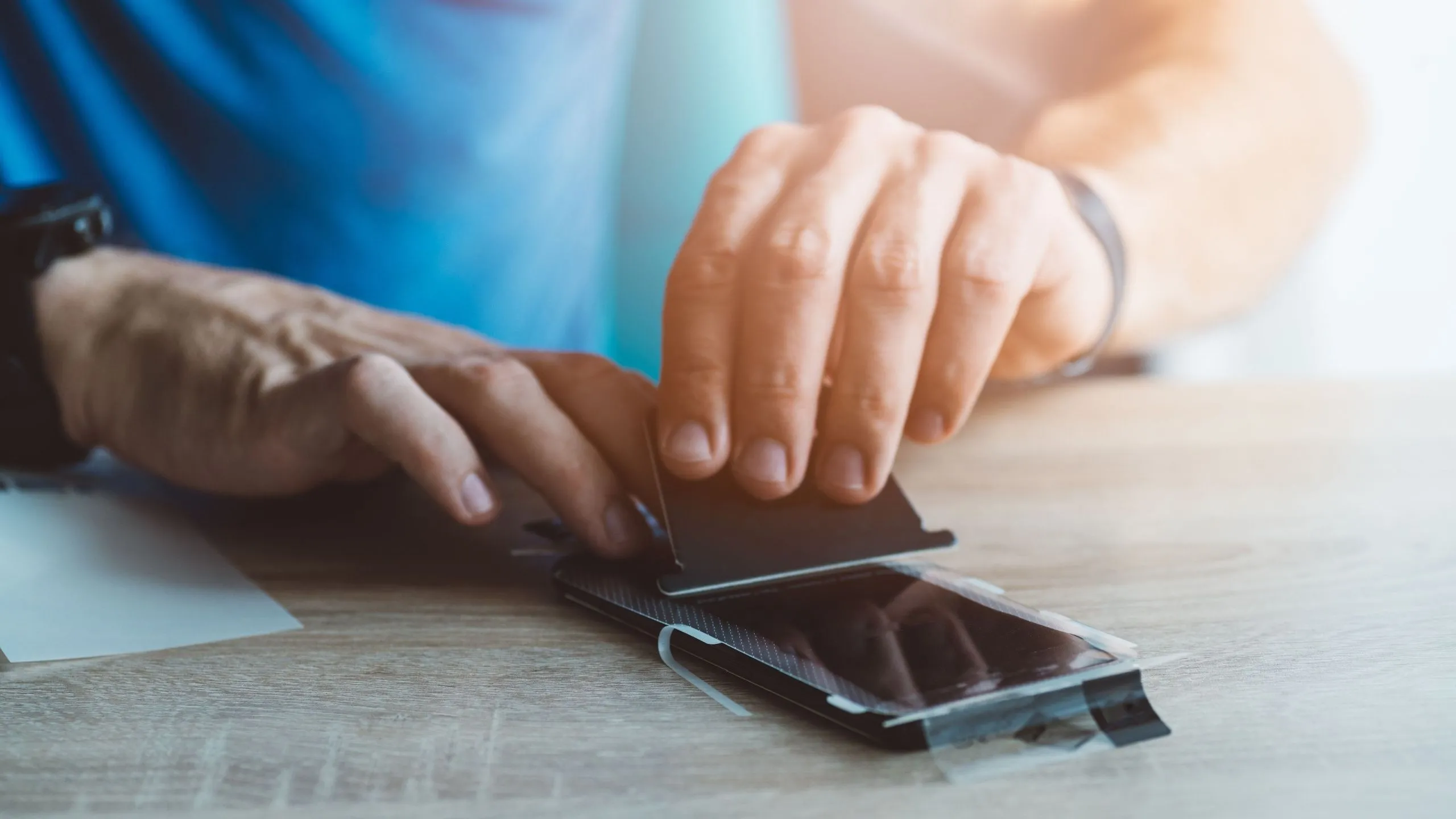 Người dùng đang dán miếng bảo vệ màn hình lên iPhone