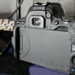 Người dùng đang nhìn qua ống ngắm quang học của máy ảnh Canon 200D DSLR để chuẩn bị chụp ảnh, thể hiện lợi thế về tầm nhìn chân thực.