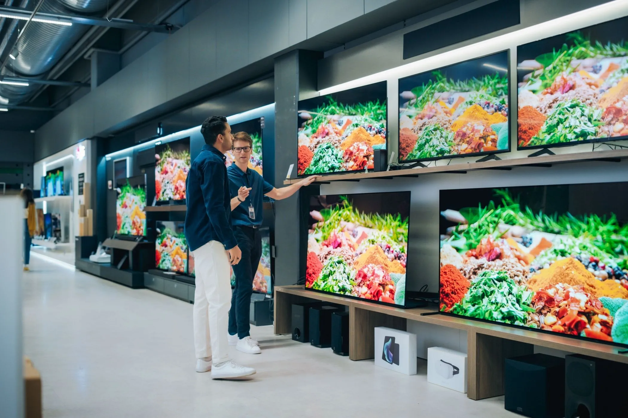 Nhân viên cửa hàng đang giới thiệu TV cho khách hàng, minh họa các ưu đãi từ thẻ thành viên