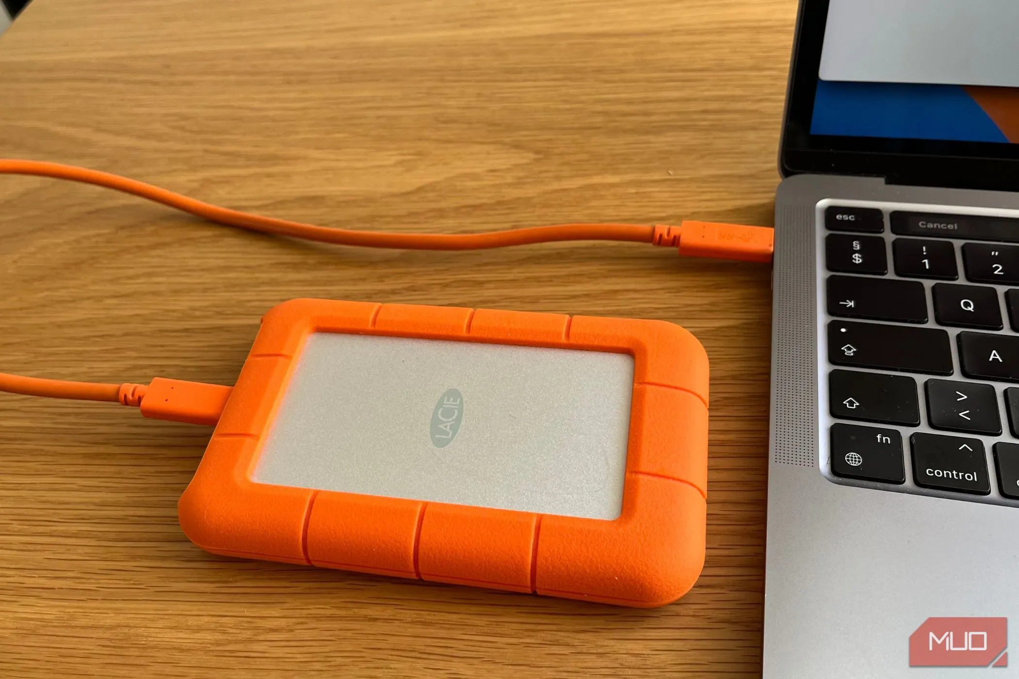 Ổ cứng ngoài di động màu đen được cắm vào cổng USB của một chiếc máy tính xách tay màu bạc, minh họa cách sao lưu dữ liệu trực tiếp.