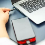 Phụ nữ cắm cáp USB-C vào laptop từ sạc dự phòng để sạc nhanh