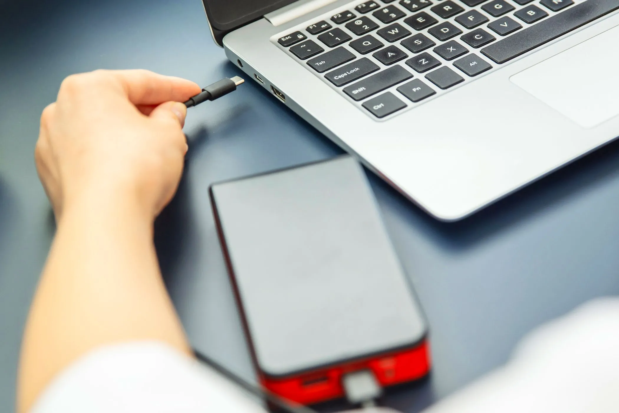 Phụ nữ cắm cáp USB-C vào laptop từ sạc dự phòng để sạc nhanh