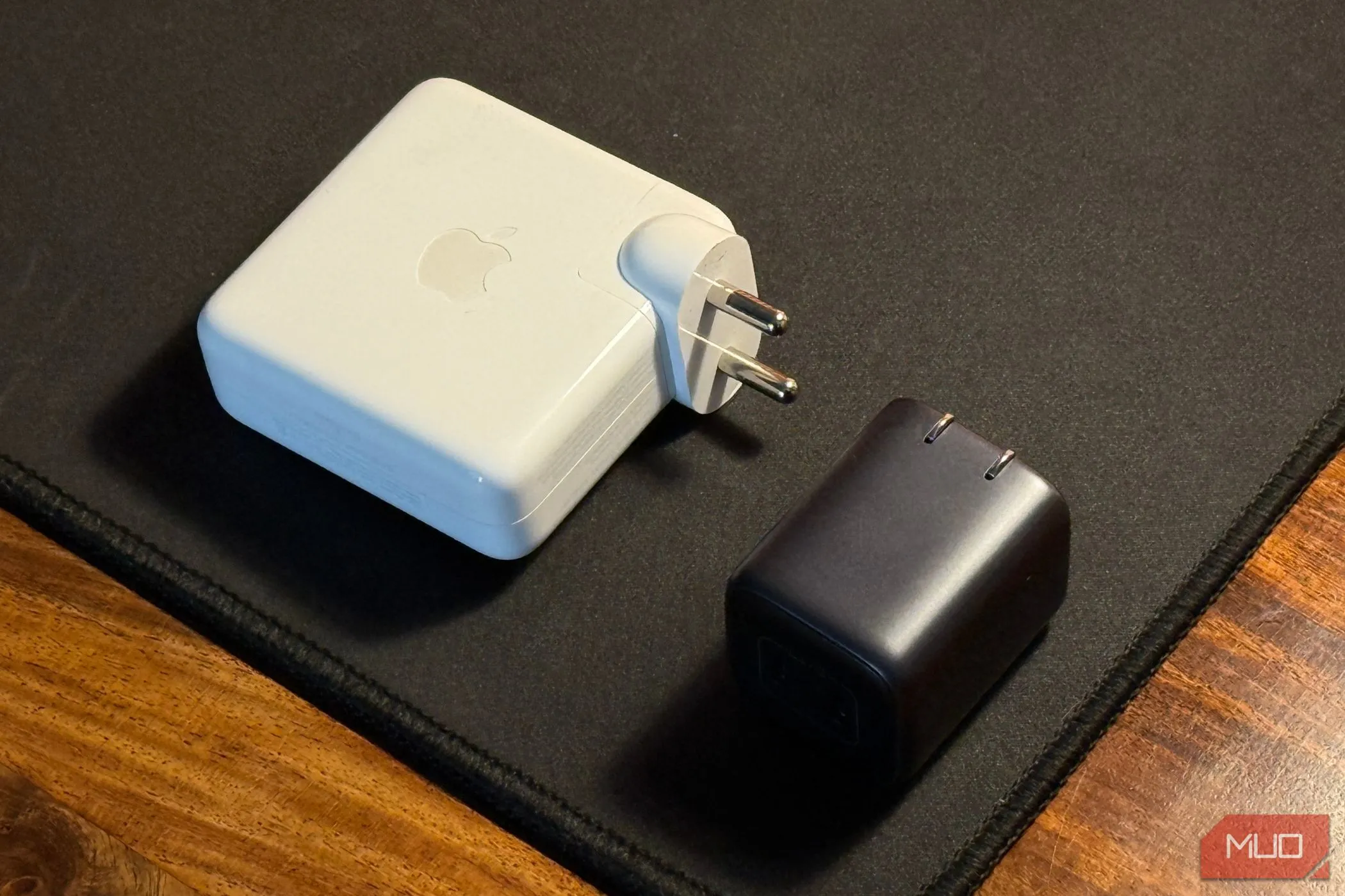 So sánh kích thước củ sạc GaN nhỏ gọn và cục sạc MacBook Pro lớn, minh họa lợi ích của sạc du lịch.