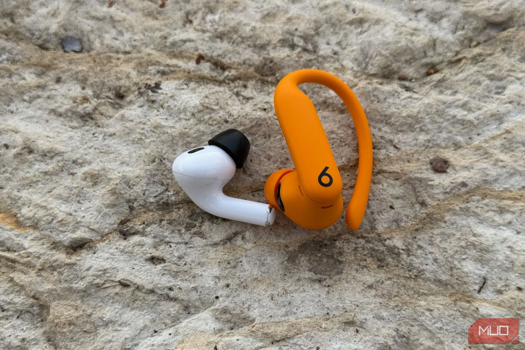 So sánh trực quan trọng lượng và thiết kế giữa AirPods Pro 2 và Powerbeats Pro 2, nhấn mạnh sự khác biệt về kích thước.