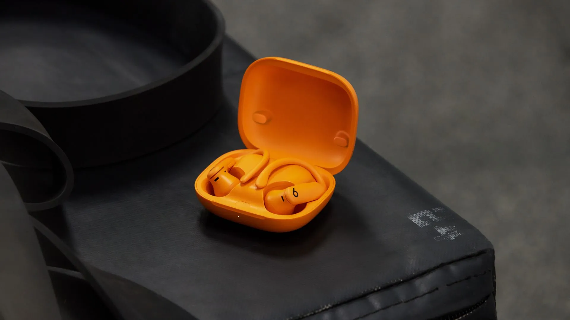 Tai nghe Powerbeats Pro 2 màu cam nổi bật với thiết kế móc tai, minh họa tính năng theo dõi nhịp tim.
