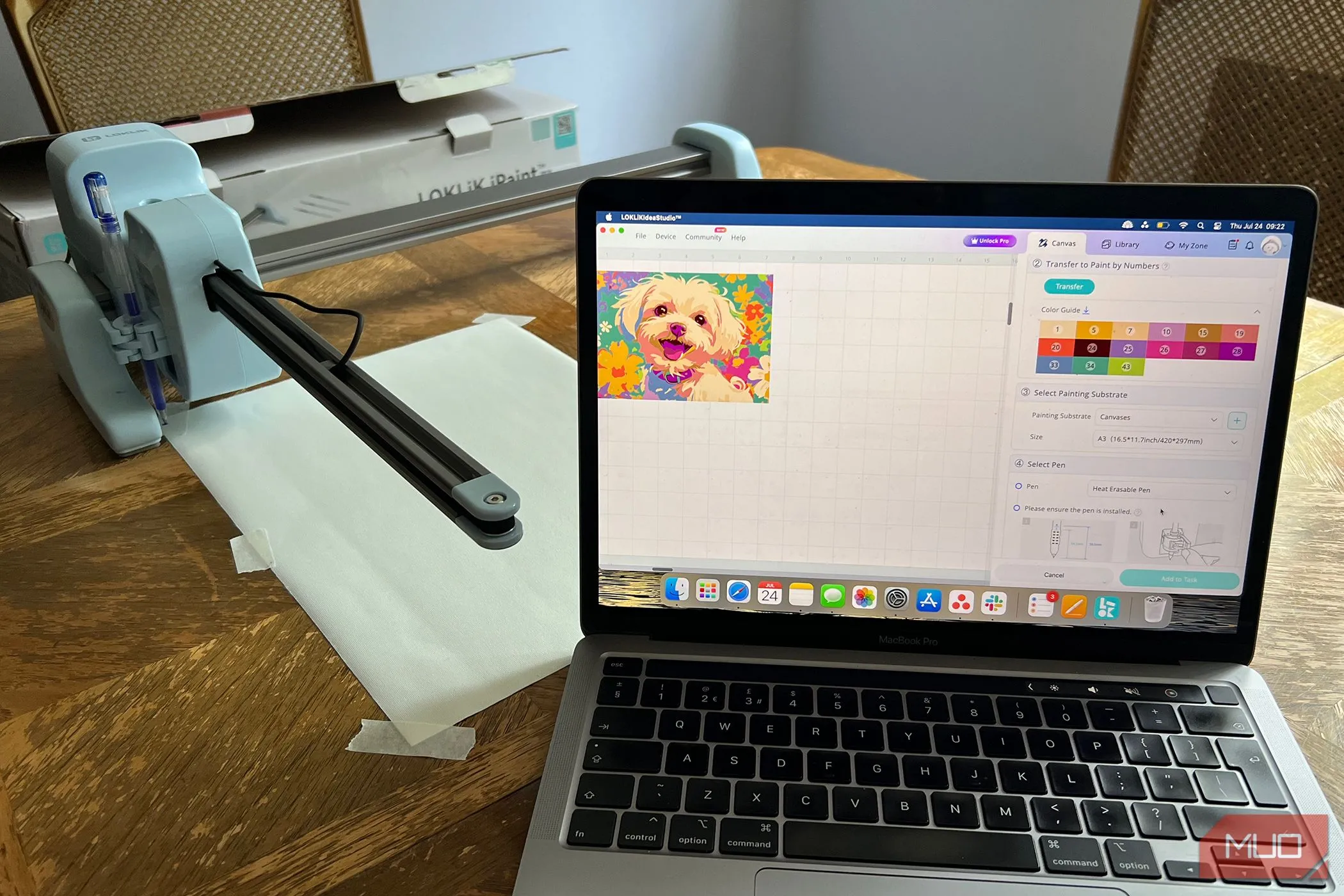 Thiết bị LOKLiK iPaint sẵn sàng vẽ trên canvas trống, bên cạnh MacBook hiển thị ảnh gốc.